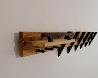 May include: A wooden wall-mounted shelf with a black metal handle and multiple black metal triangular hooks.