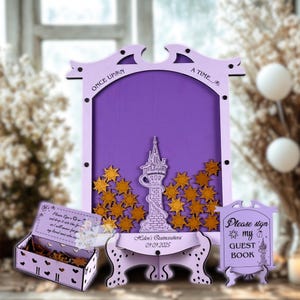 Puede incluir: Un juego de libro de visitas de madera de color lila claro con un diseño de torre y estrellas. El juego incluye un letrero, una caja y un marco con el texto "Once Upon A Time..." y "Please sign my guest book". La fecha "09.09.2025" también es visible.