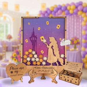 May include: Wooden guest book set with a princess theme. The set includes a sign-in board with a silhouette of a princess and a tower, a heart-shaped sign that says "Please sign my guest book", and a box for the guest book pieces. The board is 18 inches tall.