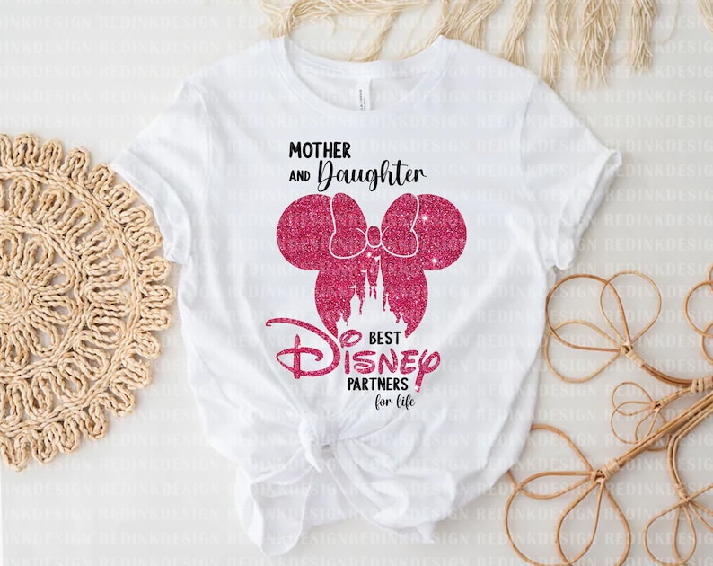 May include: White t-shirt with pink glitter Mickey Mouse ears and a bow. The text "Mother and Daughter Best Disney Partners for Life" is printed on the shirt.