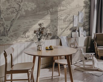 May include: A light wood dining table with a round top and four legs. Two chairs and a stool are placed around the table. The table is set with a white mug and lemons. The background features a wall with a wood paneling design and a wallpaper with a black and white landscape scene.