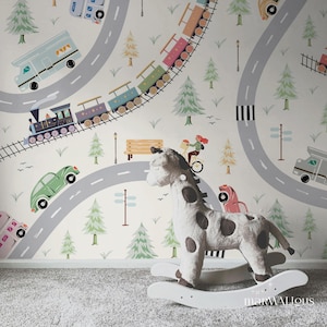 May include: A soft giraffe rocking horse on a white base is positioned in front of a playful wallpaper. The wallpaper depicts roads, trains, cars, trees, and a person on a bicycle, creating a fun, imaginative scene.