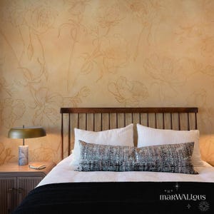 Puede incluir: Una cama blanca con una cabecera de madera y una almohada de tiro con estampado en blanco y negro. La pared detrás de la cama está pintada de amarillo claro y presenta un diseño floral.