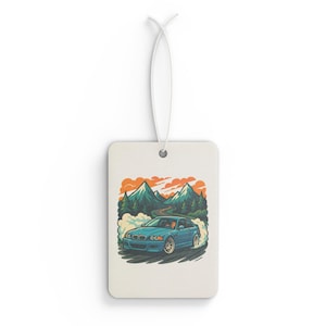 May include: A blue car with a driver drifting on a mountain road with smoke coming from the tires. The car is surrounded by green trees and mountains in the background. The sky is orange and yellow.
