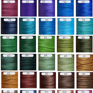 May include: A grid of forty-five spools of thread in various colors, each labeled with a white rectangular tag containing a black number. The colors range from white, yellow, orange, and red to various shades of pink, purple, blue, green, and brown.