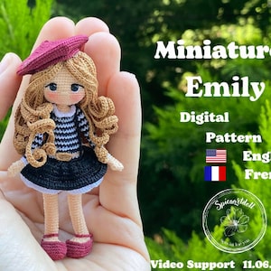 May include: Crochet doll pattern for a miniature doll named Emily. The doll is wearing a red beret, a striped shirt, and a black skirt. The pattern is available in English and French. The image includes the text "Miniature Emily", "Digital Pattern", "English", "French", and "Video Support 11.06.2024".