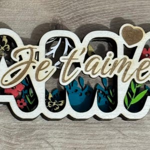 Palavra "Mãe" recortada e colada para dar um efeito de relevo. Presente de mãe, letras de madeira, Dia das Mães.
