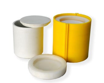 Op de afbeelding: Twee ronde containers, een witte en een gele. De witte container heeft een deksel. De gele container is open en heeft een witte voering aan de binnenkant.