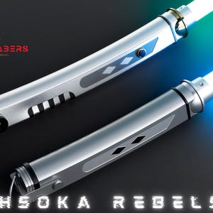 May include: Two silver lightsabers with glowing white and blue blades. The hilts have intricate designs with black accents and blue buttons. The text "AHSOKA REBELS" is displayed at the bottom.