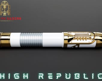 May include: A white and gold lightsaber with silver accents. The lightsaber has a cylindrical design with intricate detailing and the text "HIGH REPUBLIC" in green. The Astro Sabers logo is in the top left corner.