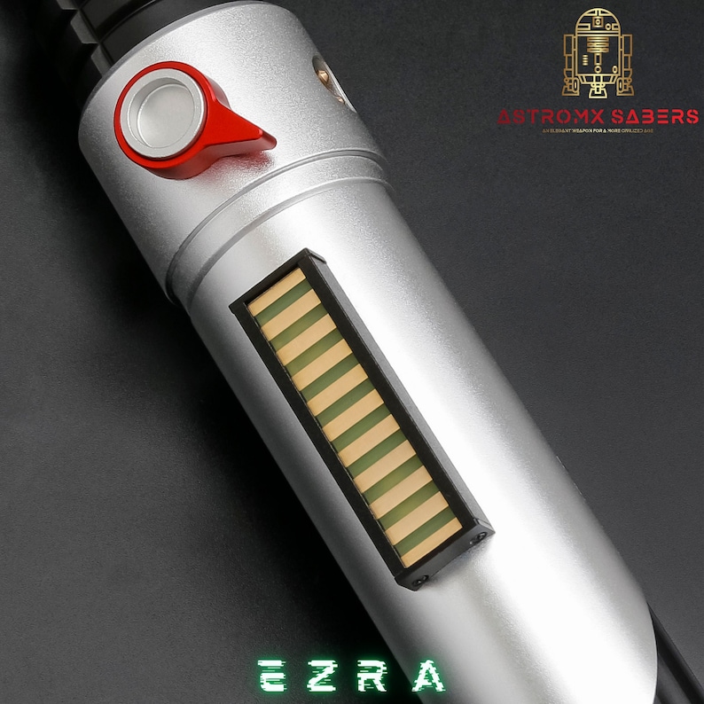 May include: Silver lightsaber with a red activation switch and a rectangular display with green and yellow stripes. The text "EZRA" is displayed in green at the bottom. The lightsaber is a prop from Astromx Sabers.