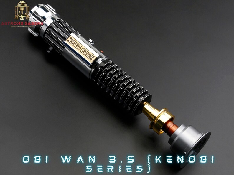 May include: A silver and black lightsaber with a gold connector and a grey end cap. The lightsaber is disassembled and the parts are laid out on a grey surface. The text "OBI WAN 3.5 (KENOBI SERIES)" is printed in blue on the surface.