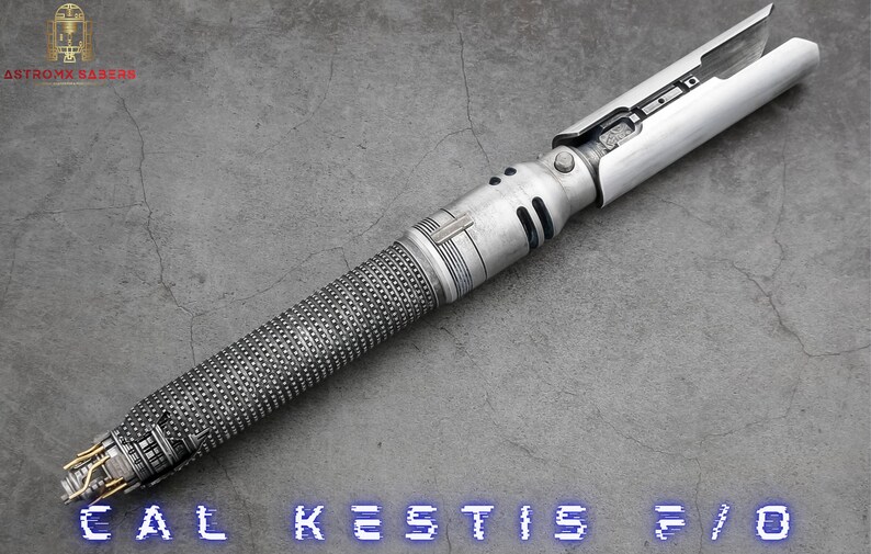K&ouml;nnte beinhalten: Ein silbernes Lichtschwert mit einem strukturierten Griff und einem schwarzen und silbernen Griff. Das Lichtschwert ist mit "CAL KESTIS F/O" beschriftet.