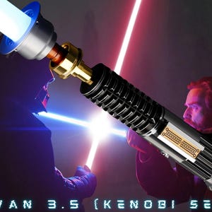 May include: A black lightsaber with a silver handle and a gold accent. The lightsaber is lit with a blue blade and is being held by a person in the background. The text "OBI WAN 3.5 (KENOBI SERIES)" is visible at the bottom of the image.