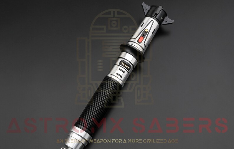Puede incluir: Un sable de luz plateado y negro con un mango negro acanalado y un bot&oacute;n rojo. El sable de luz est&aacute; sobre un fondo gris con el texto "AN ELEGANT WEAPON FOR A MORE CIVILIZED AGE" y una imagen estilizada de R2-D2.