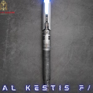 K&ouml;nnte beinhalten: Ein silbernes Lichtschwert mit einer blauen Klinge. Das Lichtschwert hat einen strukturierten Griff und einen schwarzen Knopf an der Seite. Der Text "CAL KESTIS 5/0" ist am unteren Rand des Bildes sichtbar.