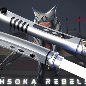 May include: Two silver lightsabers with white blades are displayed against a blurred background featuring a character from the Star Wars franchise. The lightsabers have black and silver accents and the text "AHSOKA REBELS" is visible.