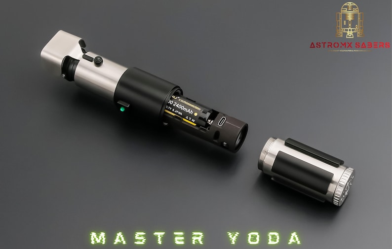 May include: A silver and black lightsaber, partially disassembled, with the text "MASTER YODA" in green neon. The hilt is open, showing the battery compartment. The Astro MX Sabers logo is in the top right corner.