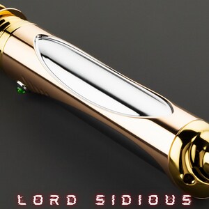 May include: A gold and silver lightsaber with the text "LORD SIDIOUS" in red. The lightsaber has a curved handle with a silver center section and a green button. The lightsaber is on a dark gray background.