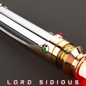 May include: A lightsaber with a silver and gold hilt, featuring red and green buttons. The blade emits a bright red glow. The text "LORD SIDIOUS" is displayed in red at the bottom. The logo of a golden droid is in the upper right corner.