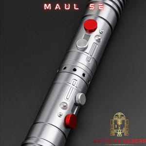 Op de afbeelding: Een zilveren lichtzwaard met rode accenten, met de tekst "MAUL SE" in het rood. Het lichtzwaard heeft een metallic afwerking met diverse knoppen en details. Het AstroX Sabers-logo is rechtsonder zichtbaar.