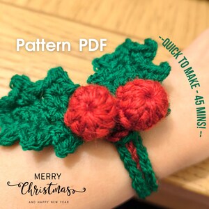 May include: A crocheted Christmas holly bracelet with green leaves and red berries. The text "Pattern PDF" and "Merry Christmas" are visible. The text "Quick to make - 45 mins!" is also visible.