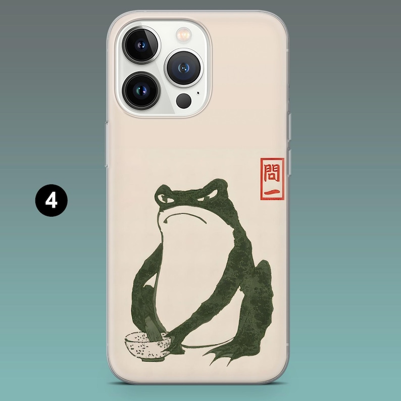 Pode incluir: Capa de telem&oacute;vel com um design de inspira&ccedil;&atilde;o japonesa. Apresenta um sapo verde escuro com uma express&atilde;o zangada, segurando uma tigela. O design inclui um selo vermelho e uma est&eacute;tica minimalista. A capa tem uma borda transparente e um fundo bege.