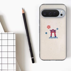 Puede incluir: Una funda transparente para tel&eacute;fono con un dise&ntilde;o de inspiraci&oacute;n japonesa. La funda presenta un fondo beige con una puerta torii roja, una flor rosa y detalles azules. Un l&aacute;piz negro y un bloc de notas con un patr&oacute;n de cuadr&iacute;cula tambi&eacute;n est&aacute;n en la imagen.