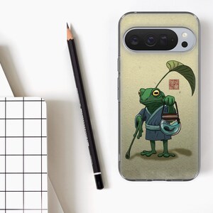Op de afbeelding: Telefoonhoesje met een cartoonkikker in een blauwe jurk, met een wandelstok en een pot met een vis. De kikker heeft een blad op zijn hoofd. De achtergrond is lichtbeige.