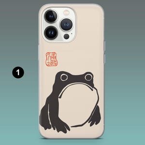 Pode incluir: Capa de telem&oacute;vel com uma ilustra&ccedil;&atilde;o de r&atilde; preta, barriga branca e olhos grandes. O design inclui um selo vermelho sobre um fundo bege. Desenhado para um smartphone.
