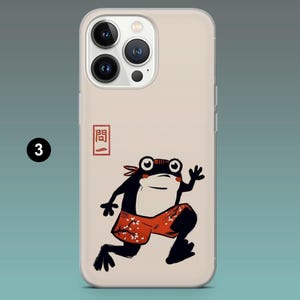 Pode incluir: Capa de telefone com um design de sapo de desenho animado. O sapo &eacute; preto e branco com cal&ccedil;&otilde;es vermelhos e uma bandana vermelha. A capa tem um fundo bege e um caractere japon&ecirc;s.