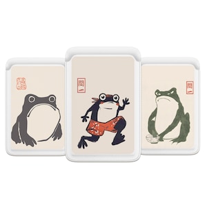 Puede incluir: Tres tarjeteros para teléfono con ilustraciones de ranas. El primero presenta una rana gris, el segundo una rana corriendo con pantalones cortos rojos y el tercero una rana verde con un cuenco. Cada tarjetero tiene un borde blanco y un fondo beige.