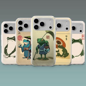 Op de afbeelding: Een verzameling van vijf telefoonhoesjes met Japans ge&iuml;nspireerde kikkerillustraties. Elk hoesje toont een uniek kikkerontwerp, met verschillende kleuren en poses, tegen een neutrale achtergrond. De hoesjes zijn transparant met een beschermende bumper.