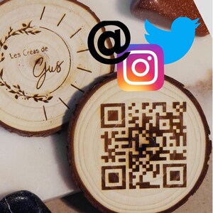 Peut inclure: Deux dessous de verre en bois clair. L'un présente un code QR, l'autre le texte "Les Créas de Gus" et un motif floral. Des icônes de réseaux sociaux, dont Instagram et Twitter, sont également visibles.