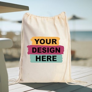 May include: A white drawstring bag with a design that says "YOUR DESIGN HERE" in black text on a yellow, pink, and blue background.