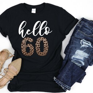 May include: Black t-shirt with the text "hello 60" in white. The number 60 is in a leopard print pattern.