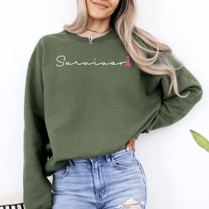 May include: A green sweatshirt with the word "Survivor" in white script and a pink ribbon graphic.