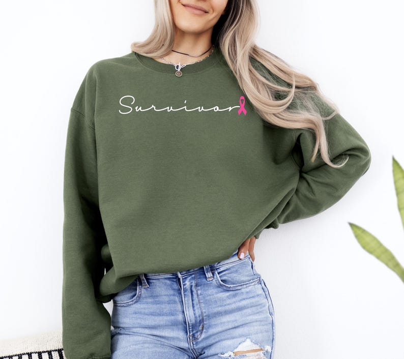 May include: A green sweatshirt with the word "Survivor" in white script and a pink ribbon graphic.