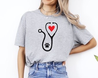 May include: A gray t-shirt with a black and red stethoscope design. The stethoscope has a paw print on the end and a red heart in the middle.