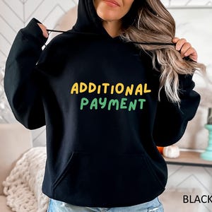 May include: Black hoodie with the text "ADDITIONAL PAYMENT" in yellow and green lettering.