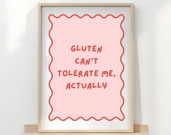 May include: A framed print with a light pink background and a wavy red border. The text "GLUTEN CAN'T TOLERATE ME, ACTUALLY" is written in red. The frame is a light wood color, and the print is displayed on a small shelf.