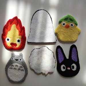 May include: Six felt patches with different characters from the movie 'My Neighbor Totoro'. The characters include Totoro, the soot sprites, the cat bus, and a chick.