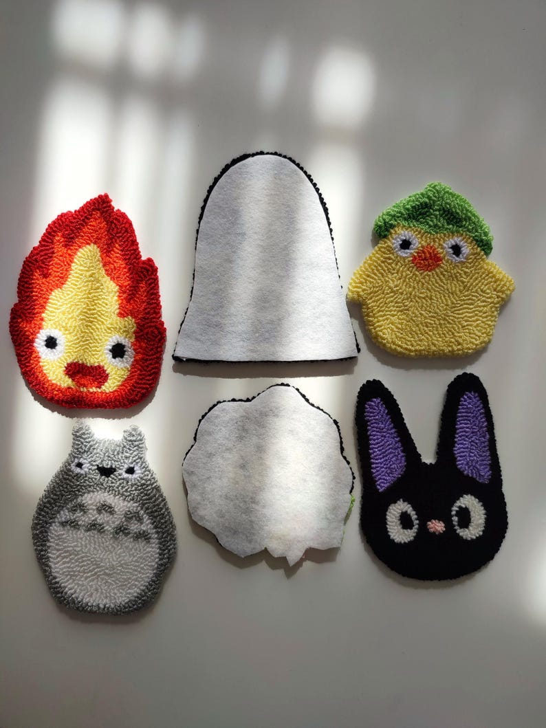 May include: Six felt patches with different characters from the movie 'My Neighbor Totoro'. The characters include Totoro, the soot sprites, the cat bus, and a chick.