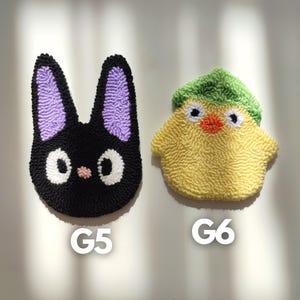 May include: Two handmade plush toys, one black cat with purple ears and white eyes, and one yellow chick with a green hat and orange beak. The toys are labeled G5 and G6.