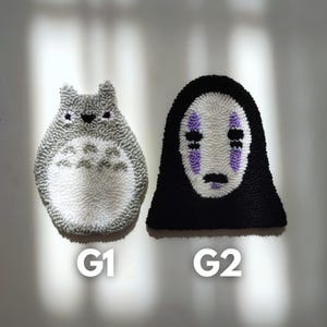 May include: Two handmade plush wall hangings, one is a white and gray Totoro character and the other is a black No Face character from the movie Spirited Away. The hangings are labeled G1 and G2.