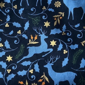 May include: Blue and gold fabric with a repeating pattern of stylized reindeer, stars, and floral designs. The background is dark blue and the reindeer are light blue.