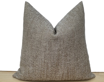 May include: A brown and beige throw pillow with a textured fabric.