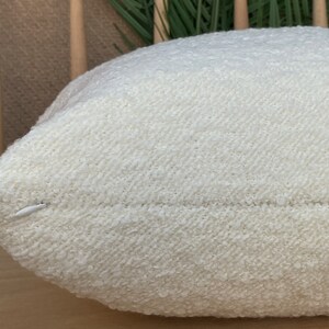 May include: A white, fluffy pillow with a textured surface. The pillow is made of a soft, comfortable material and has a subtle sheen.
