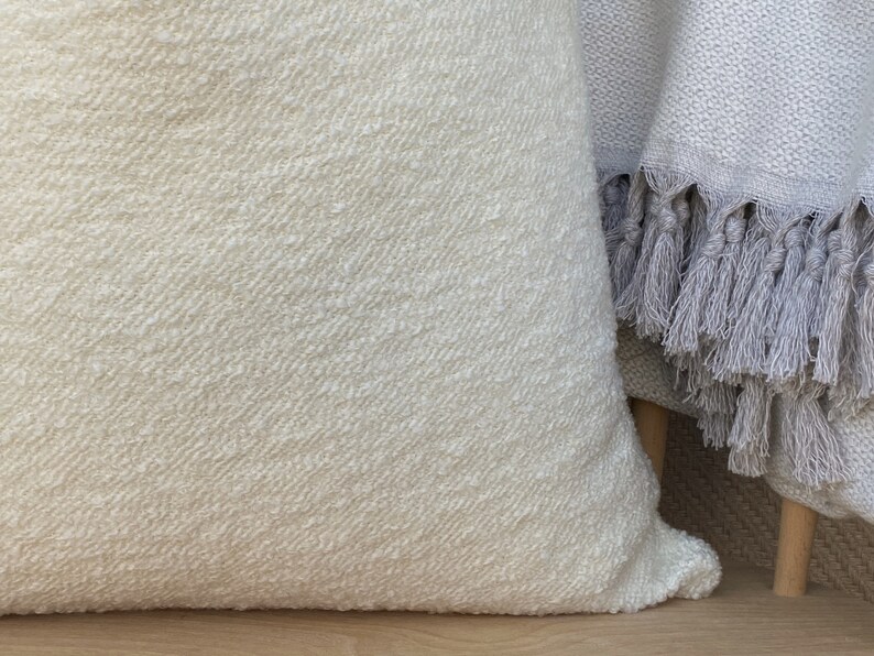 May include: A white throw pillow with a textured surface. The pillow is made of a soft, woven fabric.