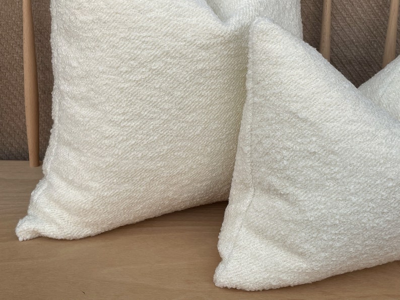 May include: Two white throw pillows with a textured surface. The pillows are made of a soft, fluffy material.